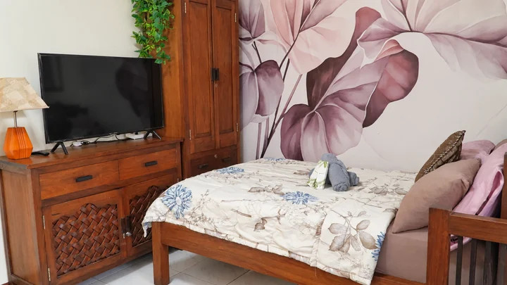Floral bedroom with fresh linens, pillows, and a television